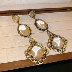 Detail view of vintage antique gold drop earrings featuring oval and square clear stones