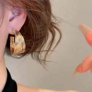 Close-up of elegant gold multi-layered hoop earring with textured design on ear