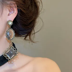 Detailed close-up view of vintage elliptical lace dangle earrings worn by a model