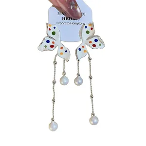 Elegante vlinder oorbellen met kleurrijke stippen en parel kwastjes.