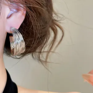 Macro detail of elegant silver multi-layer textured metal hoop earrings being worn
