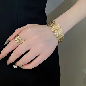 Detail view of stylish textured gold multi-layer cuff bracelet and matching wide band ring