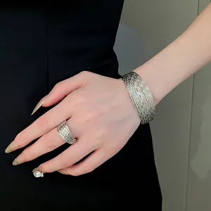 Detail of silver multi-layer textured metal cuff bracelet and matching ring on hand.