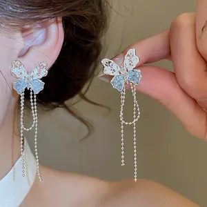 Detailopname van elegante vlinder oorbellen met zilveren filigraan en lange kettingen.