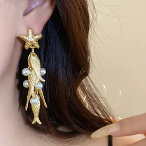 Detail shot of gold starfish and pearl fish tassel earrings on ear
