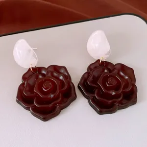 Detail von Vintage Harz-Rosenohrringen mit weißem Oberteil und dunkelrotem Blumenanhänger.
