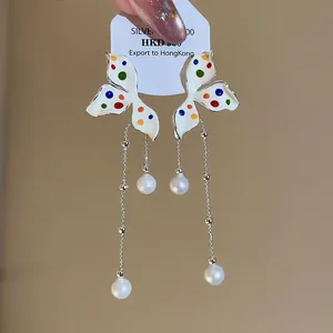 Detailweergave van Franse vlinderkwastoorbellen met kleurrijke stippen op wit emaille-ontwerp