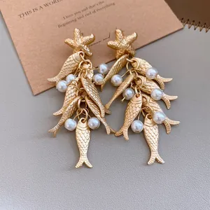 Detailed view of golden starfish stud earrings with pearl and fish tassel drop