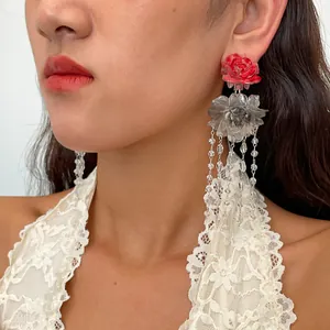 Detailed close-up of vintage resin rose and floral tassel earrings worn on the ear.