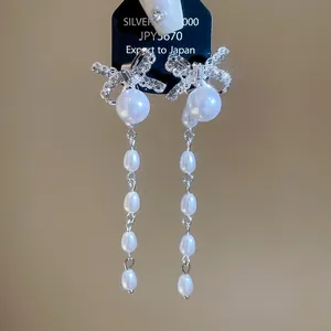 Detailopname van elegante zilveren strik oorbellen met hangende witte parels
