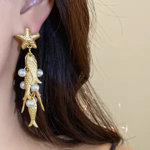 Detail shot of golden starfish and pearl fish tassel drop earrings