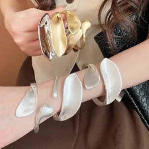 Detail shot of geometric metal leaf open bangles in matte and polished metal finishes
