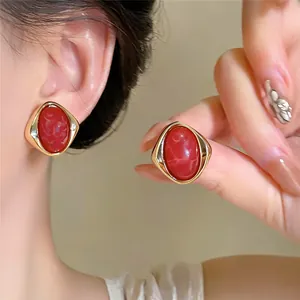 Orecchini a perno vintage ovali in marmo rosso con montatura geometrica dorata indossati