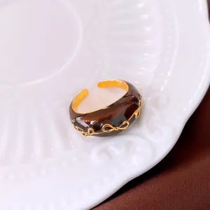 Κοντινό πλάνο επιχρυσωμένου δαχτυλιδιού 18k με καφέ σμάλτο και σχέδιο φιόγκου.