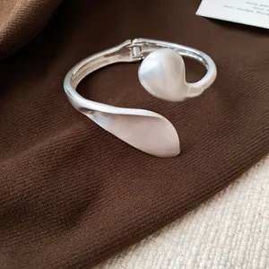 Close-up of a silver geometric leaf cuff bracelet with a matte and polished finish.