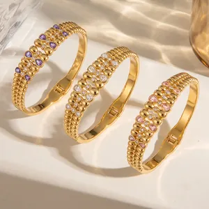 Detailansicht von drei Goldarmreifen mit lila, rosa und klaren Zirkoniasteinen