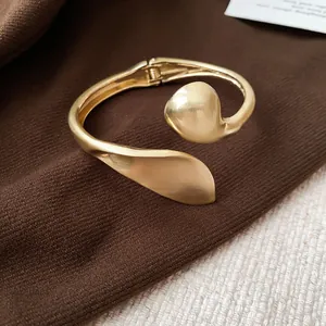 Detailed close-up of a retro geometric gold bracelet with matte and glossy finishes