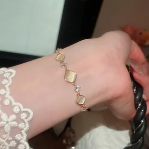 Detailopname van een gouden armband met vierkante kattenoogstenen en fonkelend zirkoon