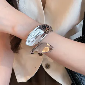 Close-up of a silver-toned organic leaf-shaped open cuff bracelet worn on a wrist