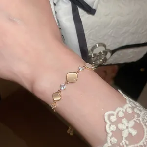 Detailopname van een verstelbare gouden armband met vierkante kattenoogstenen en zirkonia's.