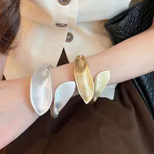 Close-up of vintage geometric leaf metal cuff bracelets in silver and gold matte finish.