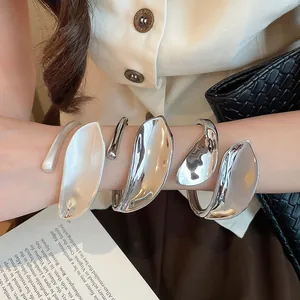 Detail view of retro geometric leaf-shaped metal open bracelets in shiny and matte silver