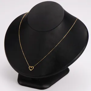 Vista detallada de un collar de acero inoxidable dorado con colgante de corazón en soporte