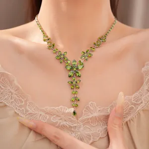 Close-up of elegant green zircon flower and teardrop necklace worn on model's neck