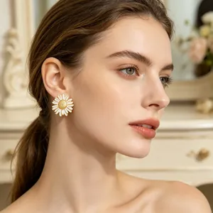 Vue détaillée d'élégantes boucles d'oreilles marguerites en émail blanc sur un modèle