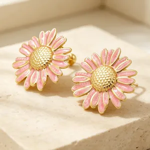 Vue détaillée de boucles d'oreilles marguerites en émail rose avec finition dorée