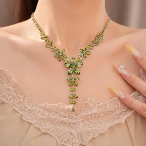 Detailed close-up of a vintage emerald green floral zircon necklace on a model's neck.