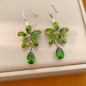 Close-up of elegant green zircon flower earrings with teardrop pendants on jewelry box