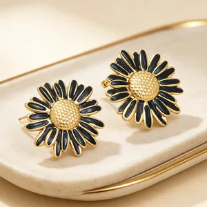 Détail rapproché de boucles d'oreilles marguerites en émail noir et doré chic