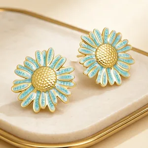 Détail de boucles d'oreilles marguerite en acier inoxydable, émail bleu clair et doré.