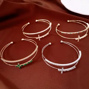Dettaglio di quattro eleganti bracciali a doppio strato placcati oro 18k con croci e zirconi