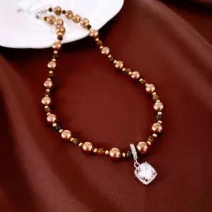Detailaufnahme einer Kette aus braunen Perlen und Tigerauge mit Zirkonia-Anhänger.