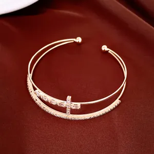Primo piano dell'elegante bracciale rigido a doppio strato in oro rosa con croce