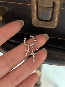 Detailansicht von silbernem 14k vergoldetem Ohrclip mit Kreuz- und Tropfenanhängern.