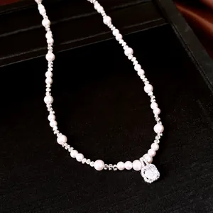 Detail van een witte parelketting met een glanzende vierkante hanger van zirkonia