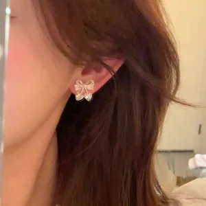 Gros plan de boucles d'oreilles nœud en zircon portées à l'oreille, bijoux style coréen