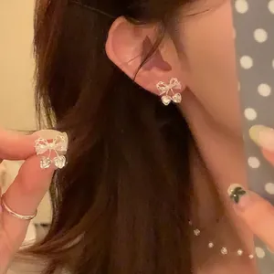Gros plan détaillé des boucles d'oreilles nœud en zircon et perles avec cœur raffiné.