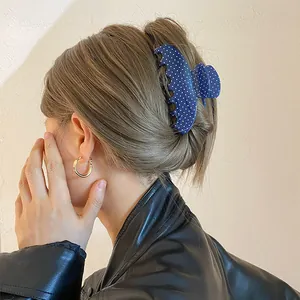 Detailweergave van een blauwe haarklem met stippen gestyled in een elegante vrouwenknot.
