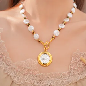 Close-up of a vintage pearl necklace featuring an embossed coin pendant on a model