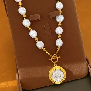 Detailed view of vintage pearl necklace featuring gold-toned portrait coin pendant.