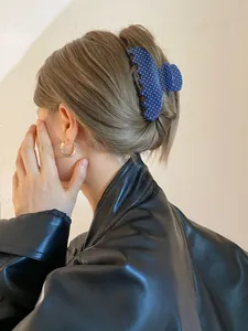 Detailweergave van een blauwe haarklem met stippen op blond haar met leren jasje