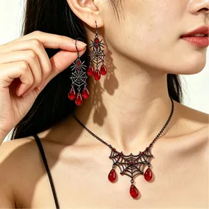 Detail van gotische spinnenweb ketting en oorbellen set met rode traandruppelstenen.