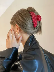 Detail van rode polkadot acryl haarklem op blond opgestoken haar