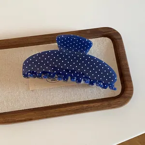 Macrodetail van een donkerblauwe acryl haarklem met een klassiek wit stippenpatroon op hout