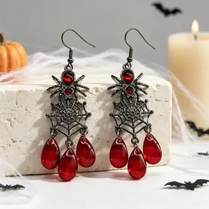 Detailopname van Halloween spinnenweb oorbellen met rode waterdruppel edelstenen.