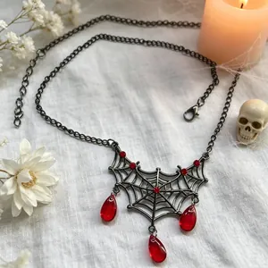Detail van gothische spinnenweb ketting met rode druppel edelstenen voor Halloween feest